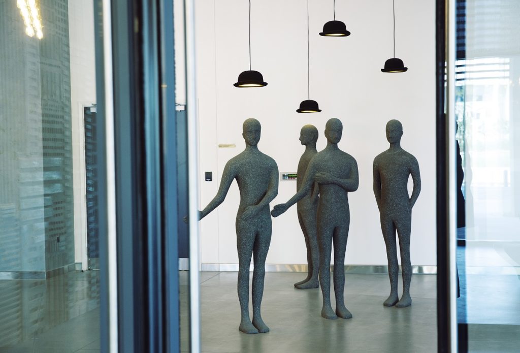 A group of human sculptures with raised hats at the lobby